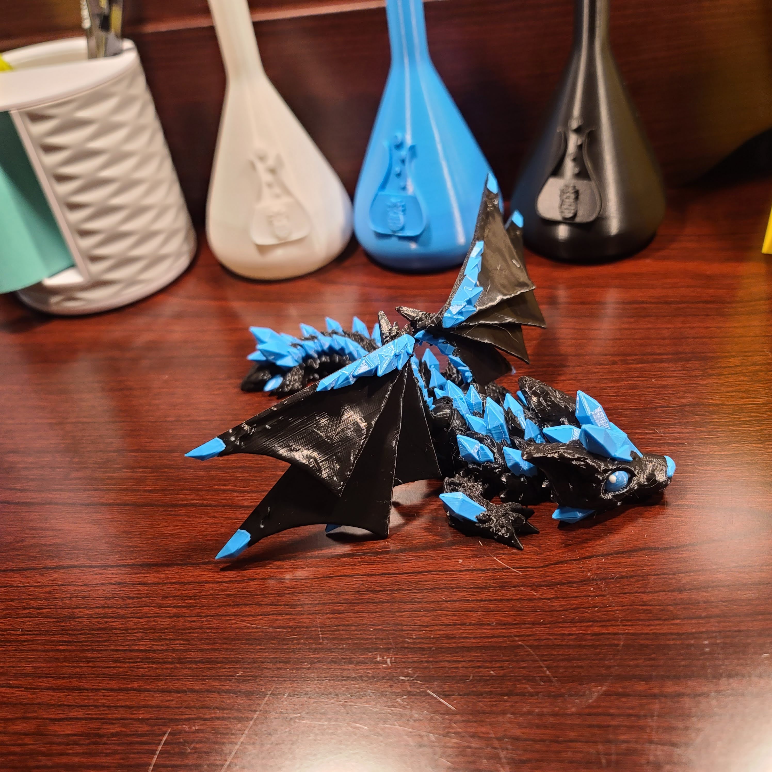 wood table with a wooden back and a crystal wolf dragon fidget with wings atop or on top of the table. The crystals are blue crystals.