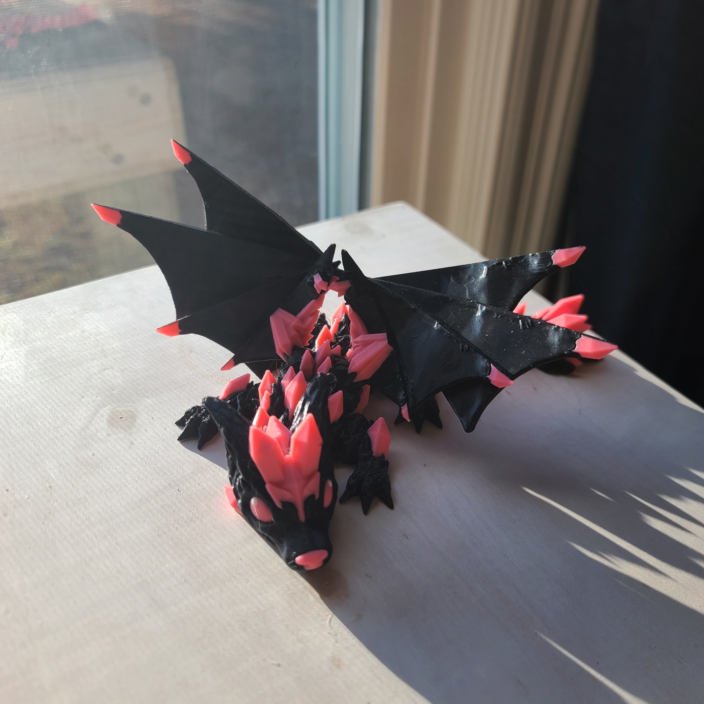 wooden table in front of a window with a crystal wolf dragon tadling or youngling with wings setting on it.