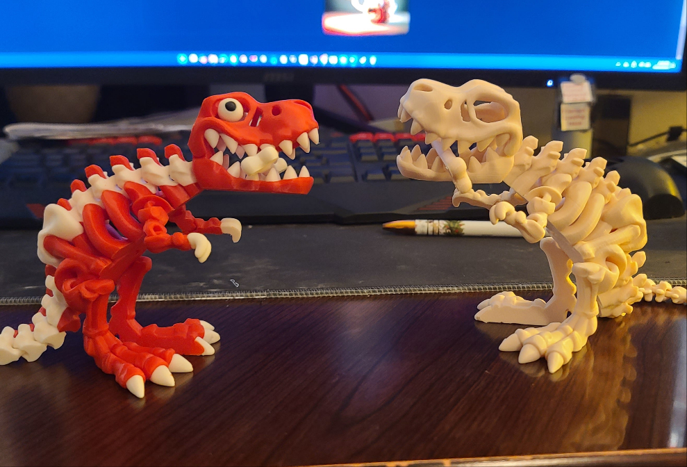 Red and white dino and dino skeleton facing eachother on computer desdk.