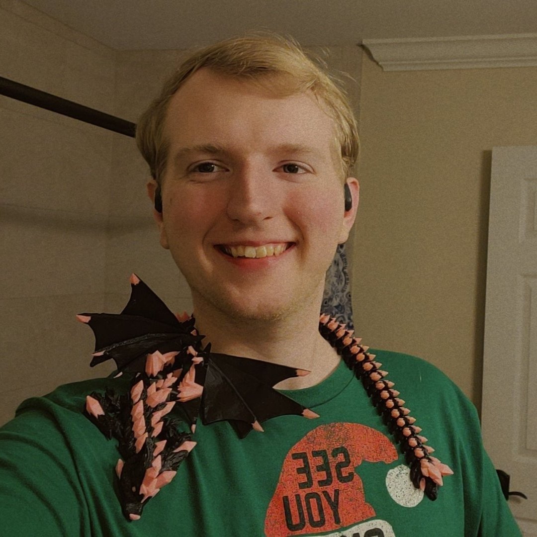 man standing in front of a shower wearing headphones and a crystal wolf dragon fidget sitting on his shoulders. the crystals on the dragon are pink.