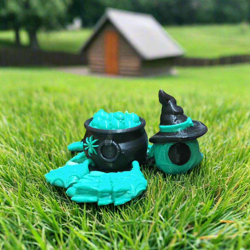 green witchurtle fidget with a black cauldron for a shell. Cauldron is bubbling and the turtle is wearing a witch hat.