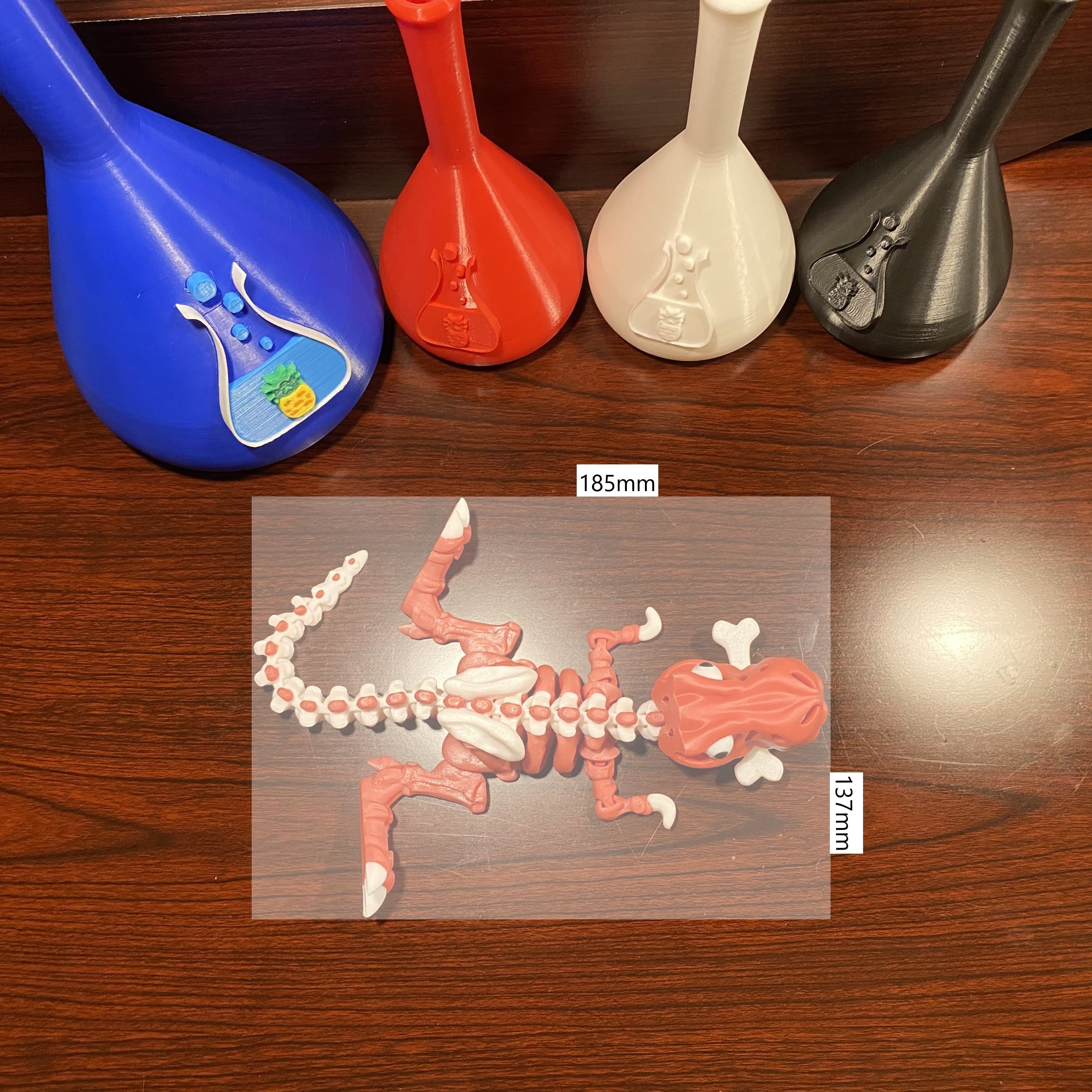 Red and white dinosaur with a bone in the mouth. 125x45mm scale overlayed. Wood background. Various beakers with chuganations logo nearby. Aerial view.