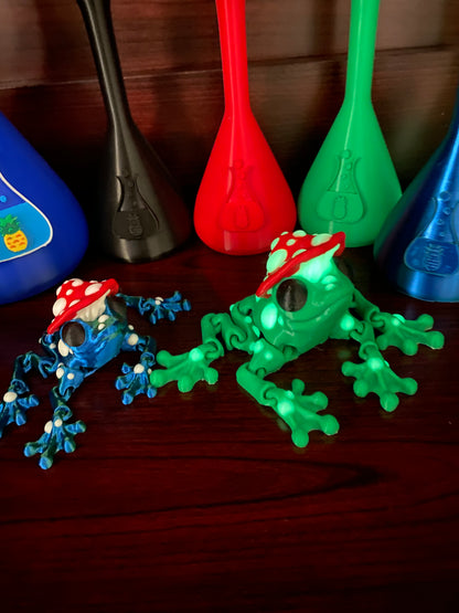 Green jumbo frog with a mushroom hat on a cherry wood desk