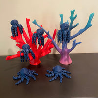 6 dark navy octopi are resting on a couple of corral reefs. All of the items in the photo are manufactured by Chuganation's 3D Lab.