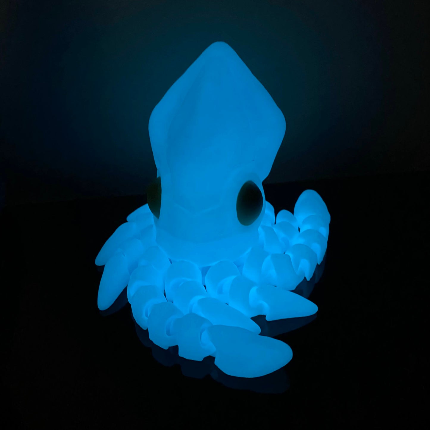 glowing blue squid fidget on a black shelf