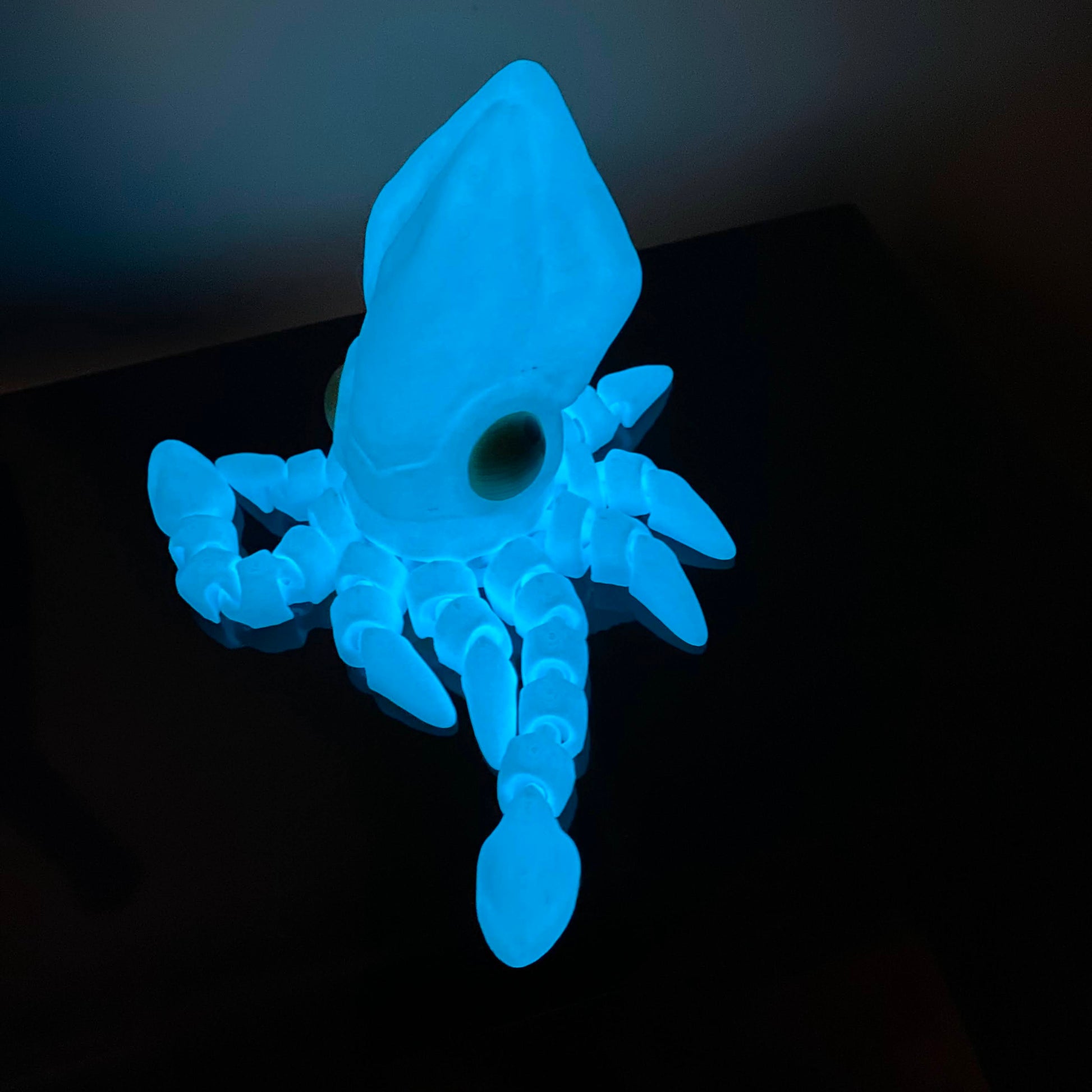 glowing blue squid fidget on a black shelf