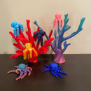 A variety octopi fidgets. 6 octopi are resting on a couple of corral reefs. All of the items in the photo are manufactured by Chuganation's 3D Lab.